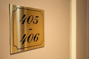 A metallic room number plaque on a wall.
