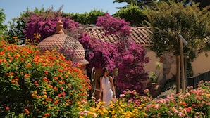 A garden with a tiled roof structure, surrounded by vibrant flowers and greenery. - Villa Miraé by Inwood Hotels - Cap d'Antibes (Antibes)