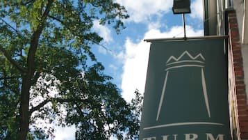 Señal del Hotel Turm con el mensaje 'Have a good time' sobre un cielo despejado y un árbol.