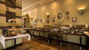 A buffet setup with various food items and a decorative wall with framed pictures and wall sconces. - Turm Hotel (Frankfurt)