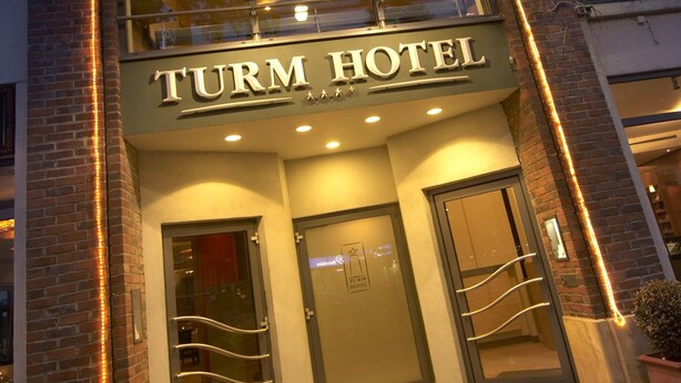 The exterior of the Turm Hotel with a modern facade, double doors, and a balcony. - Turm Hotel (Frankfurt)