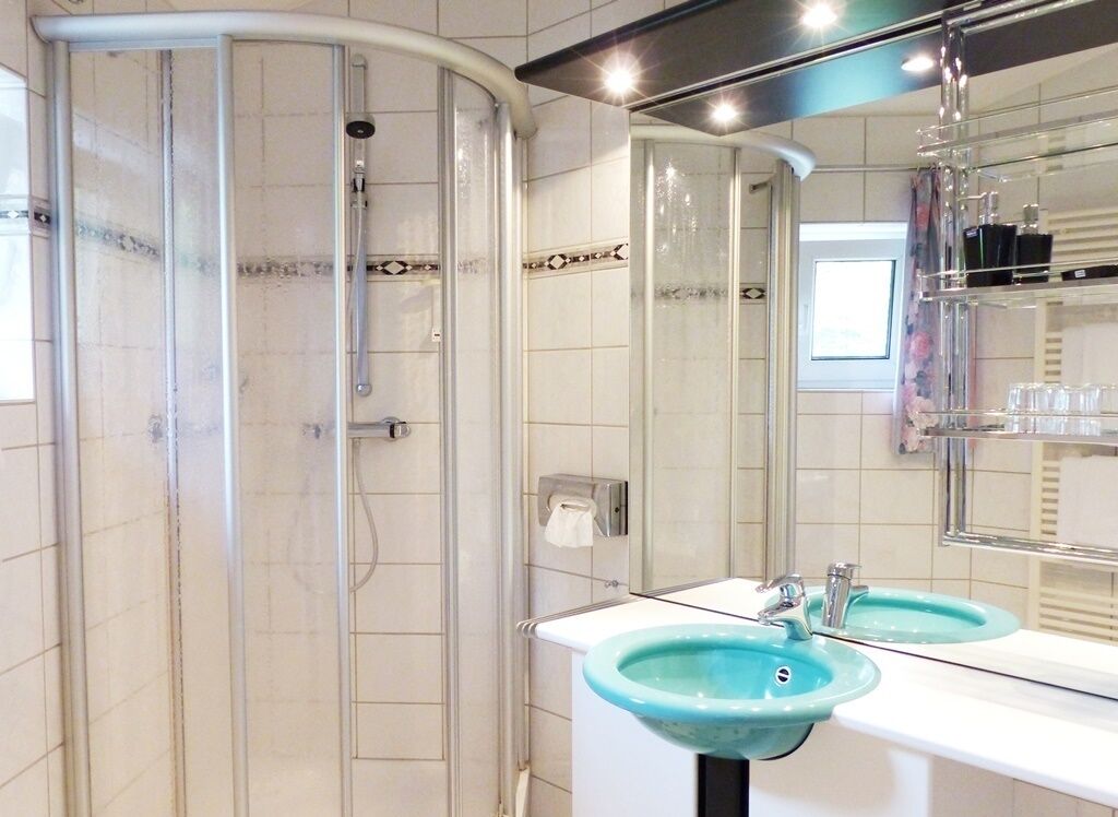 A bathroom with a glass shower enclosure, two sinks, and a mirror.