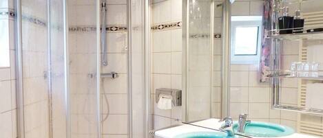 A bathroom with a glass shower enclosure, two sinks, and a mirror.