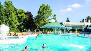 Una piscina con múltiples carriles, una fuente de agua y una zona de estar cubierta.