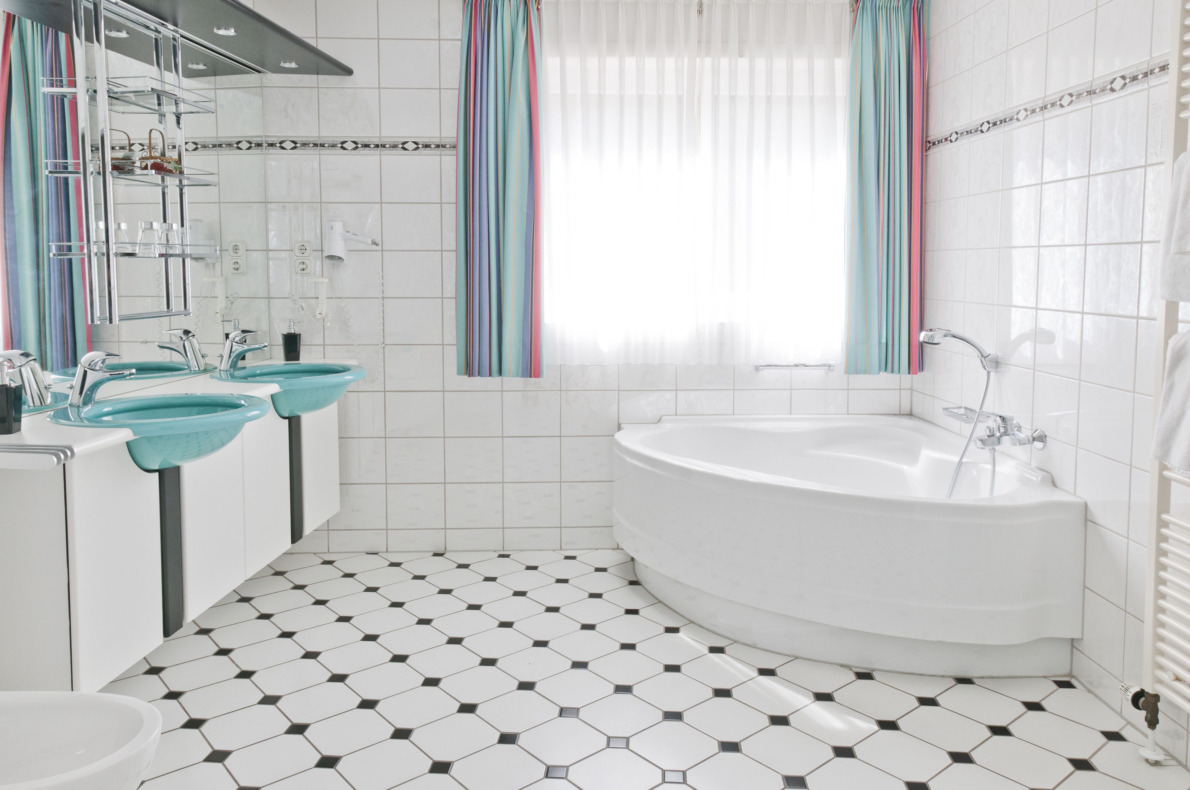 A modern bathroom with a large bathtub, two sinks, and a shower.
