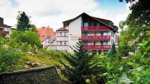 Un edificio de varios pisos con balcones, un muro de piedra y un río al frente.