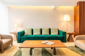 A living room with a green sofa, two side tables, a wooden coffee table, and a lamp.