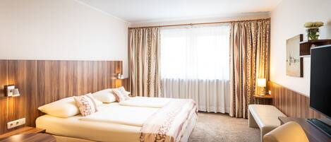 Une chambre d’hôtel avec un lit double, un bureau, une chaise et un téléviseur.