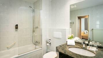 A modern bathroom with a glass-enclosed shower, a toilet, and a sink with a marble countertop.