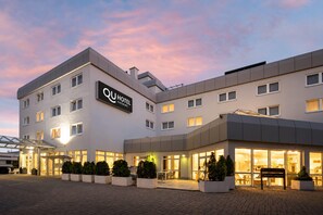 Un hotel moderno con un letrero llamativo, varios pisos y una entrada bien iluminada.