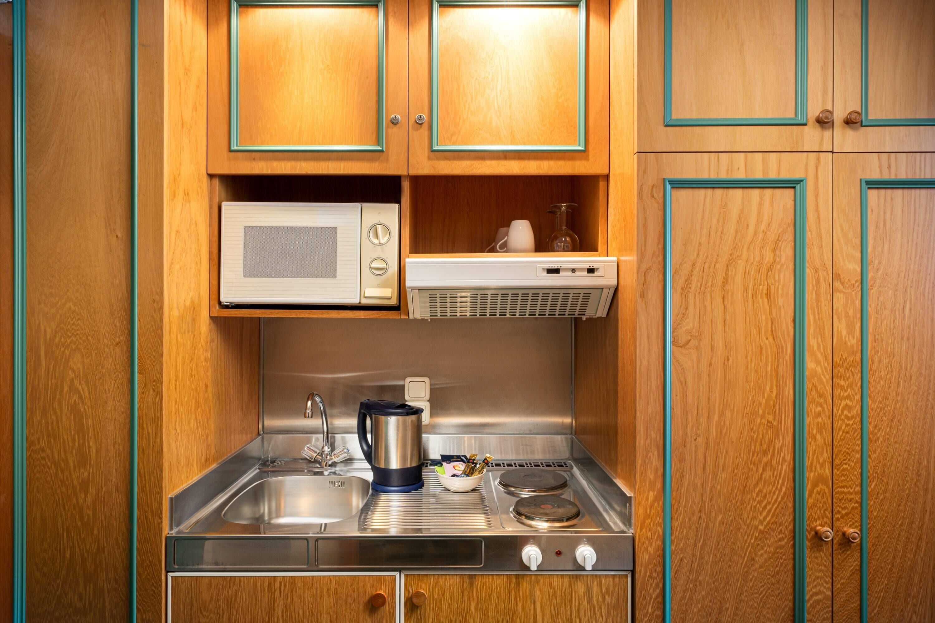 Una kitchenette compacta con microondas, estufa y pileta.