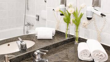 Un baño con lavamanos, espejo, toallero y secador de pelo.