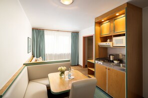 Une chambre d’h ôtel compacte comprenant un coin cuisine, un espace repas avec une table et des chaises, et un coin salon avec un canapé.