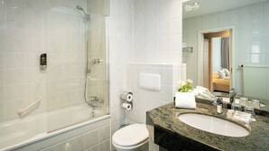Un baño moderno con ducha envuelta en vidrio, inodoro blanco y lavamanos de mármol.