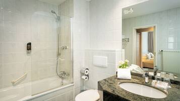 A modern bathroom with a glass-enclosed shower, a white toilet, and a marble sink.