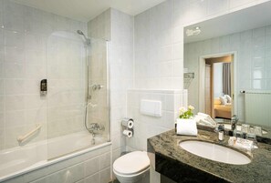 Een moderne badkamer met een douchecabine van glas, een toilet en een wastafel met een marmeren blad.