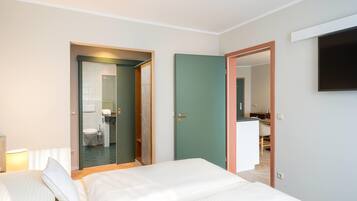 A hotel room with a bed, a desk, a chair, and a television mounted on the wall.