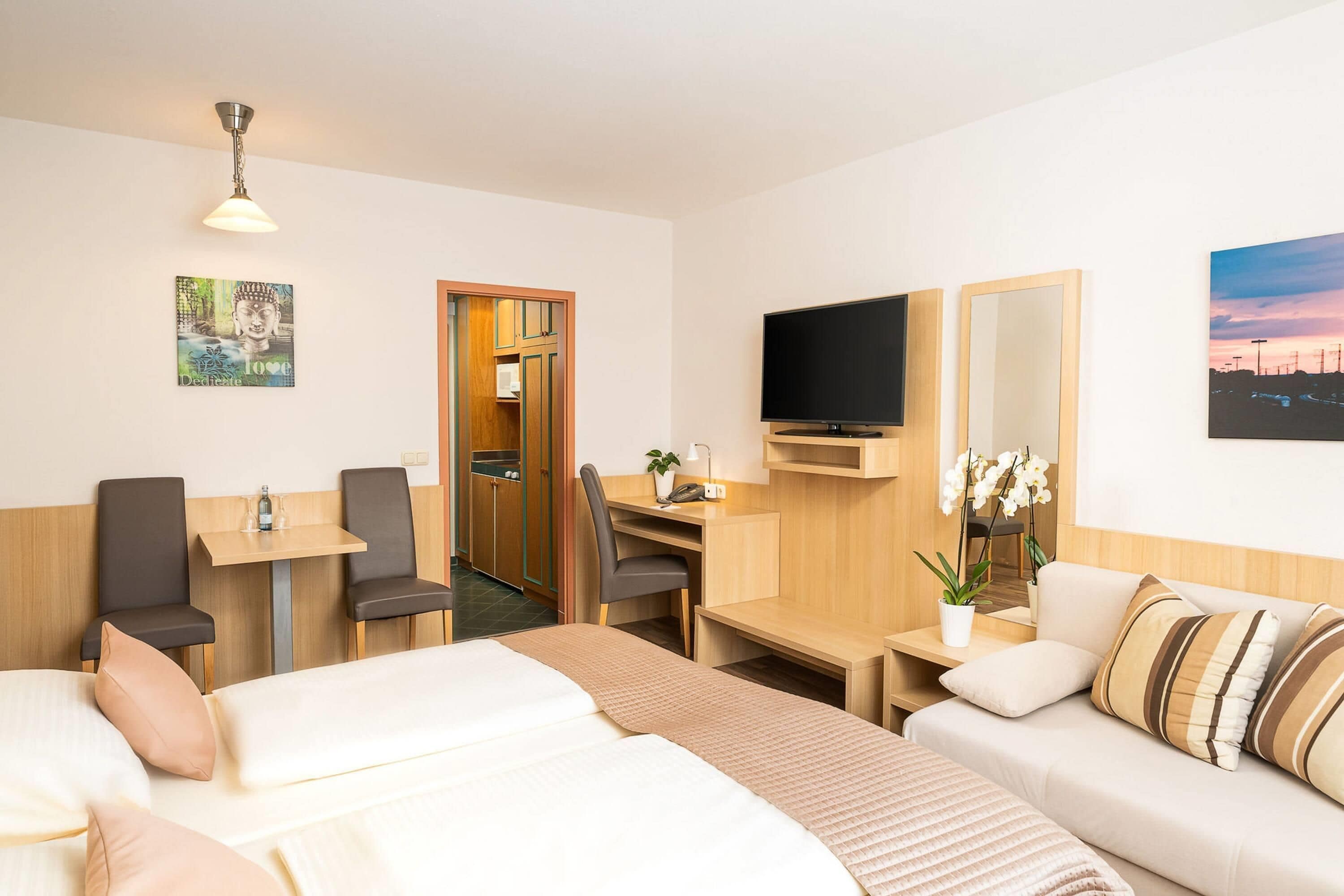 Ein Hotelzimmer mit Bett, Schreibtisch, Fernseher, einer Couch und einem Badezimmer.