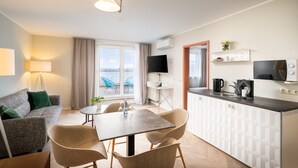 Un espacio habitable moderno y compacto, con kitchenette, comedor y sofá.