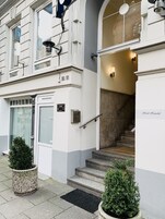 Ein Gebäudeeingang mit Treppe, einer Tür mit der Aufschrift "80/81" und einem kleinen Blumentopf.
