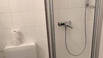 Un bagno con il water, una doccia con porta in vetro e un portasciugamani.