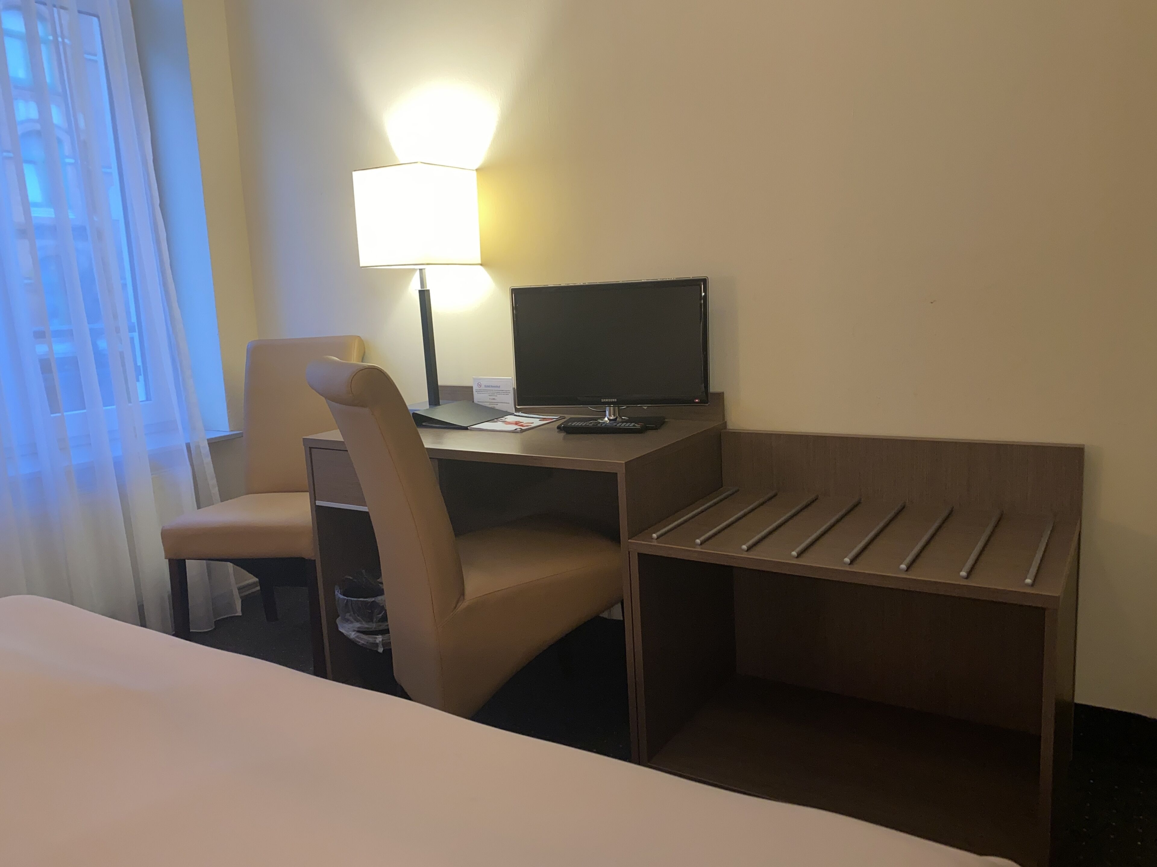 Une chambre d’hôtel avec un lit, un bureau équipé d’un ordinateur, une chaise et une lampe.