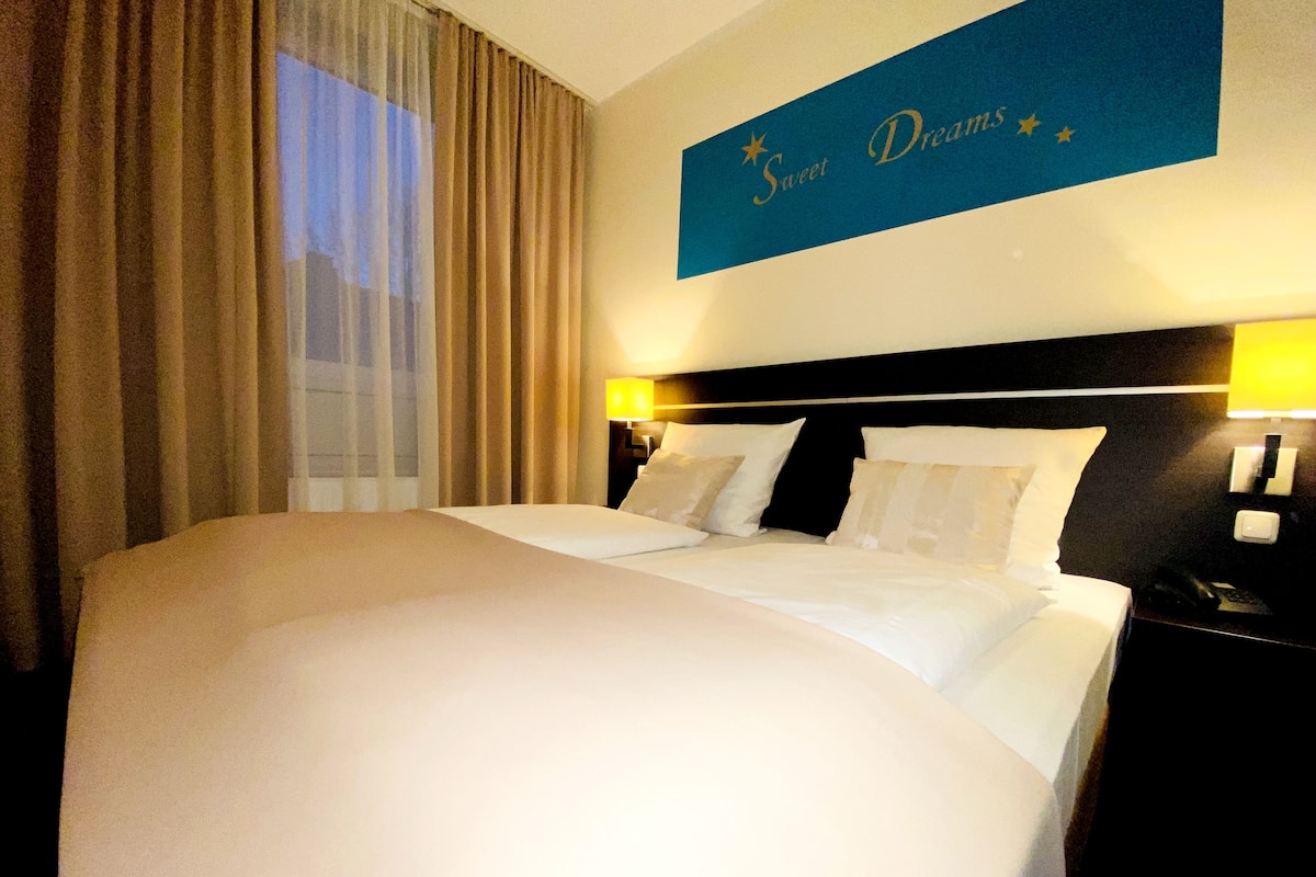 A large bed with white linens, two bedside tables with lamps, and a sign above the bed that reads "Sweet Dreams".
