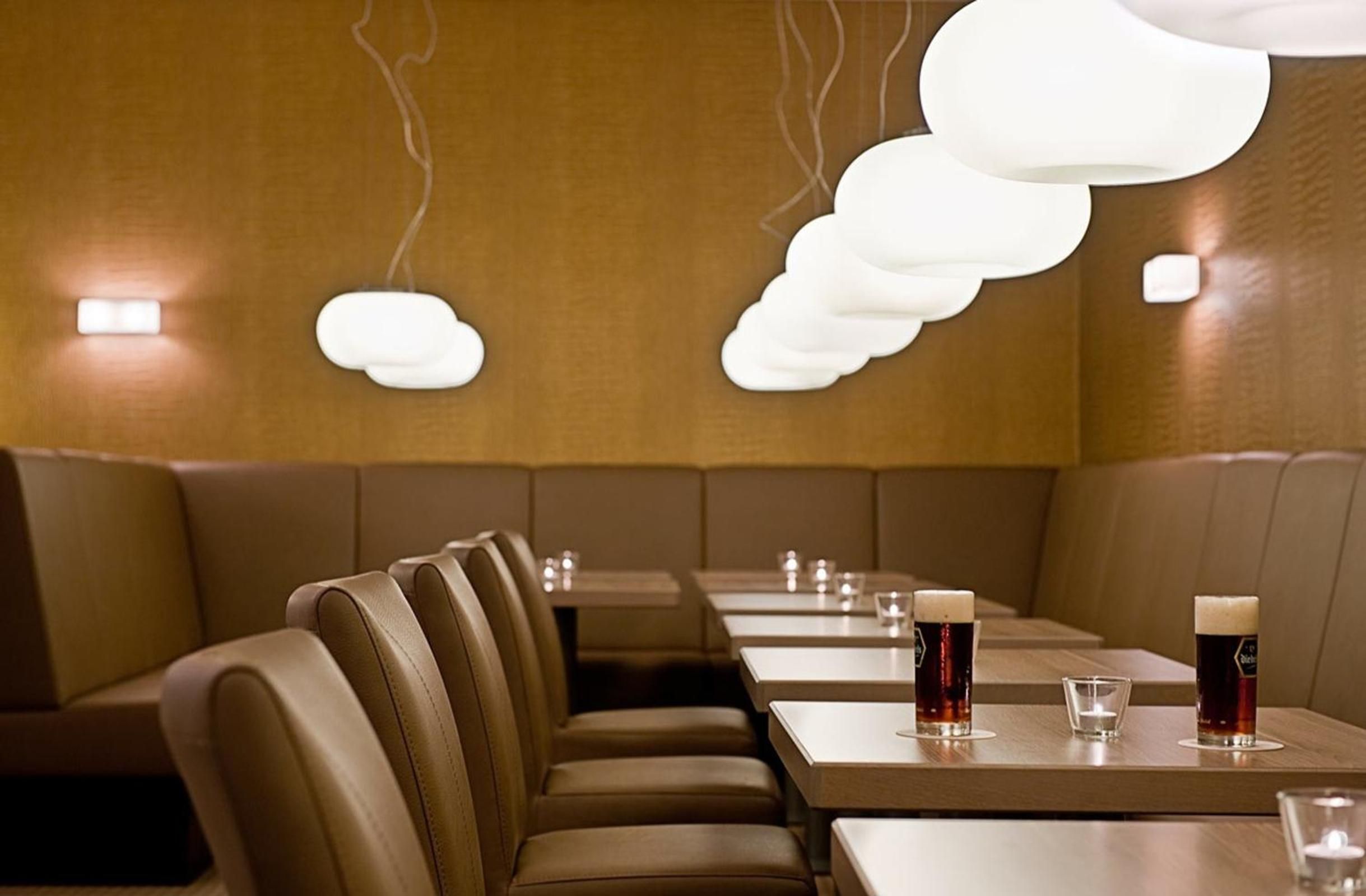 A restaurant interior with booths, tables, and hanging light fixtures.