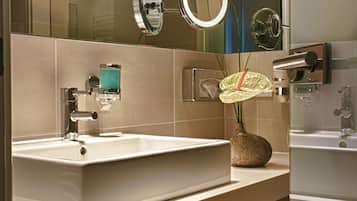 A modern bathroom with a large mirror, a sink, and a shower.