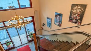 Een hotelinterieur met een trap, een kroonluchter en kunstwerken aan de muren.