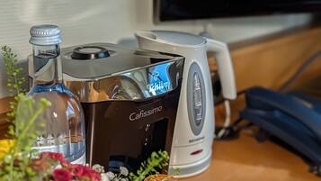 Una macchina da caffè con una bottiglia d'acqua e una piccola pianta su un piano di legno.
