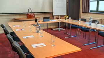 A conference room with a long table, chairs, a whiteboard, and a laptop.