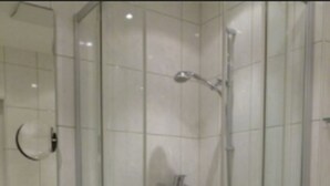 A glass-enclosed shower with a built-in sink and vanity. - Hotel Hauser (Munich)