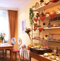 Ein Essbereich mit Tisch für zwei Personen, einem Buffet mit verschiedenen Speisen sowie einer Wand, die mit roten Flaggen und einer Uhr dekoriert ist.