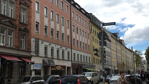 A street view with a row of multi-story buildings, including a hotel with a sign that reads "HOTEL." - Hotel Hauser (Munich)