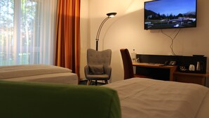 A hotel room with two beds, a desk with a chair, a TV mounted on the wall, and a window with curtains. - H+ Hotel Erfurt (Erfurt)