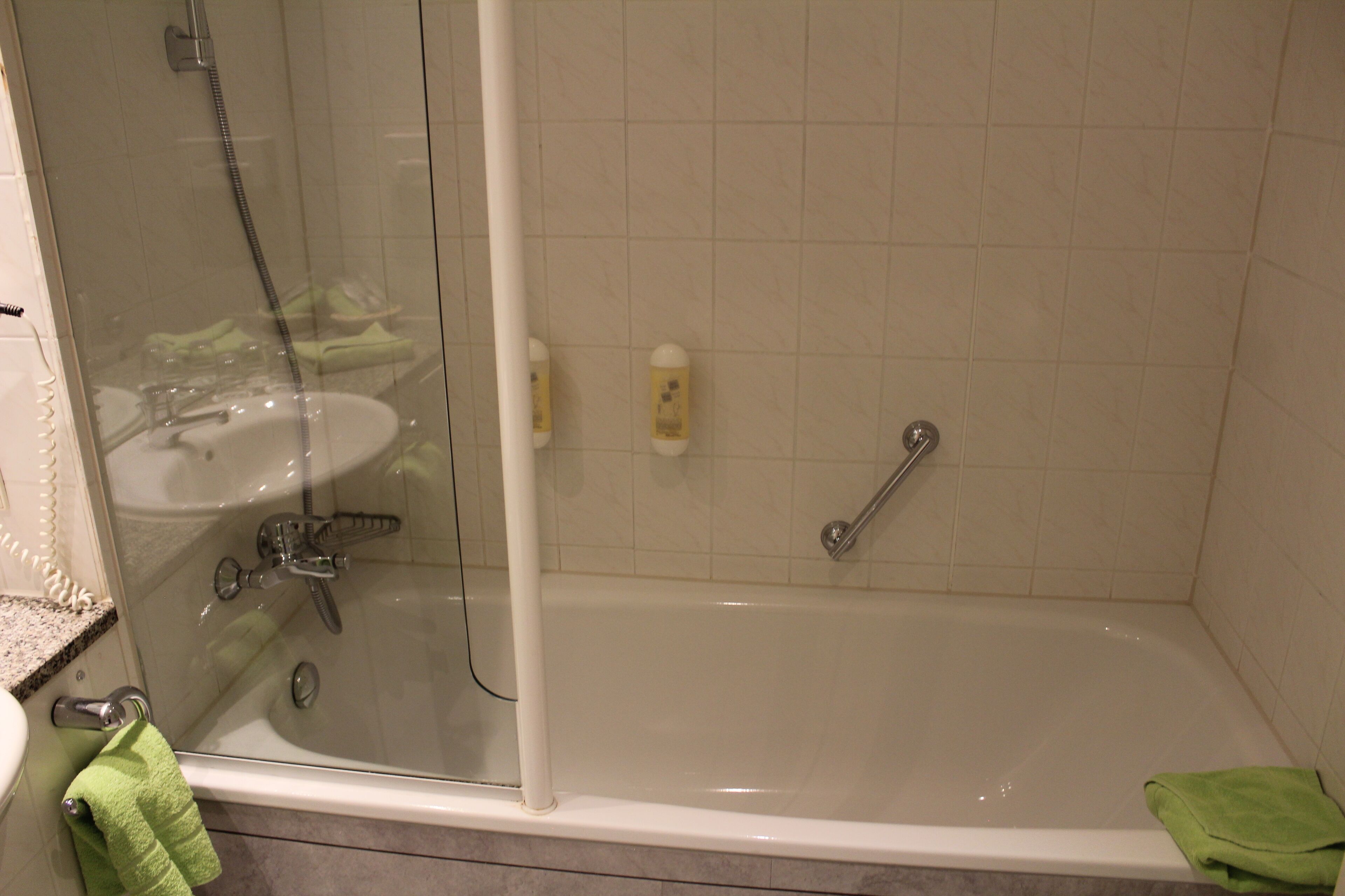 Un baño con ducha envuelta en vidrio, lavamanos y bañera.