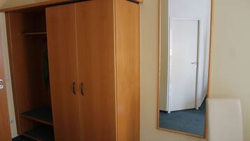 A room with a wooden wardrobe, a mirror, and a door.
