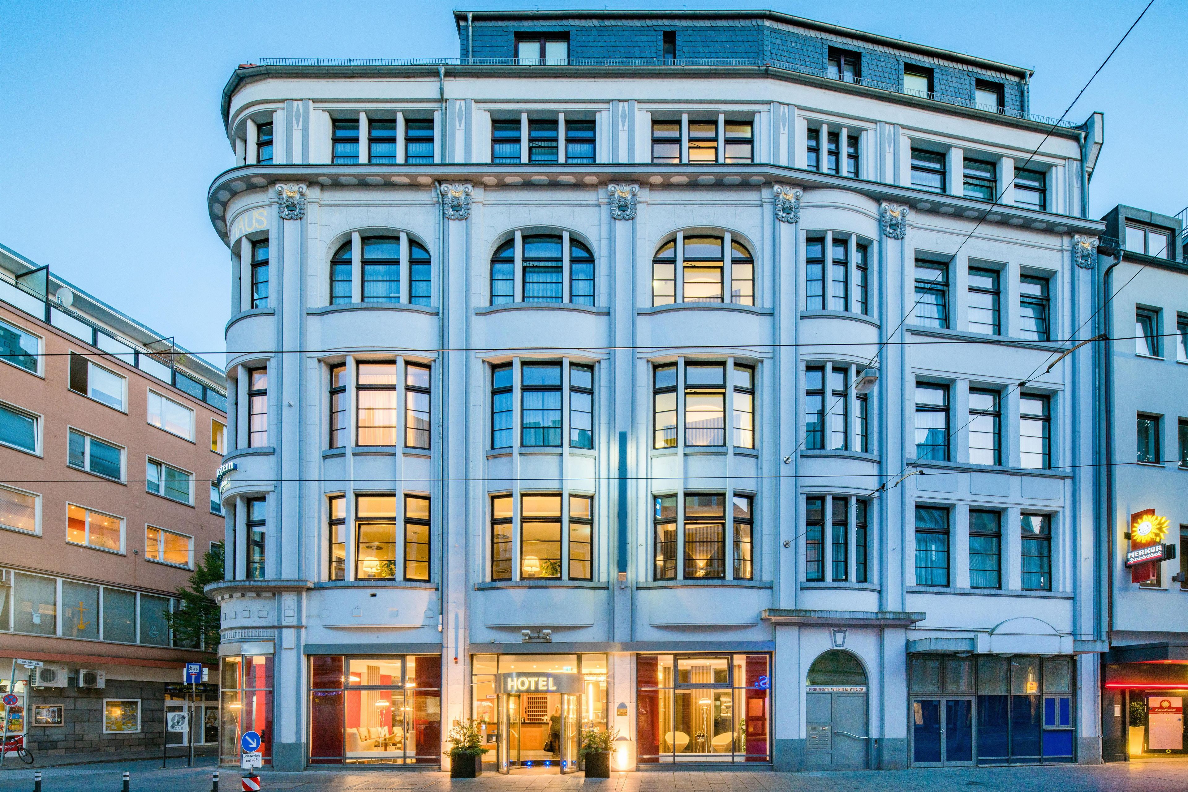 En hjørnebygning med mange vinduer, en indgang i stueetagen og et synligt skilt for et hotel.