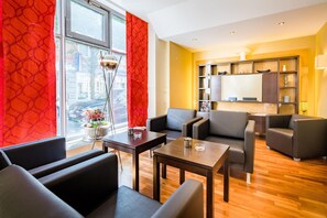 A modern living room with leather sofas, a wooden coffee table, and a view of the city through large windows. - Best Western City-Hotel Braunschweig (Braunschweig)