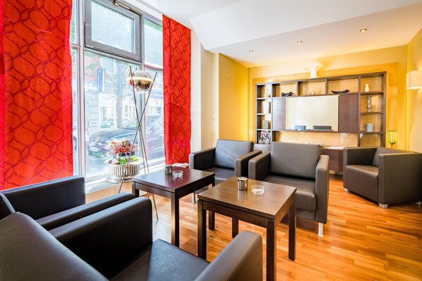 A modern living room with leather sofas, a wooden coffee table, and a view of the city through large windows. - Best Western City-Hotel Braunschweig (Braunschweig)