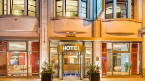 A hotel entrance with a revolving door, glass doors, and potted plants.
