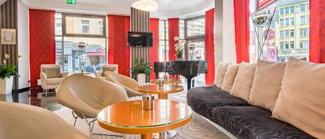 Un vestíbulo de hotel con zona de estar, un piano y un televisor.