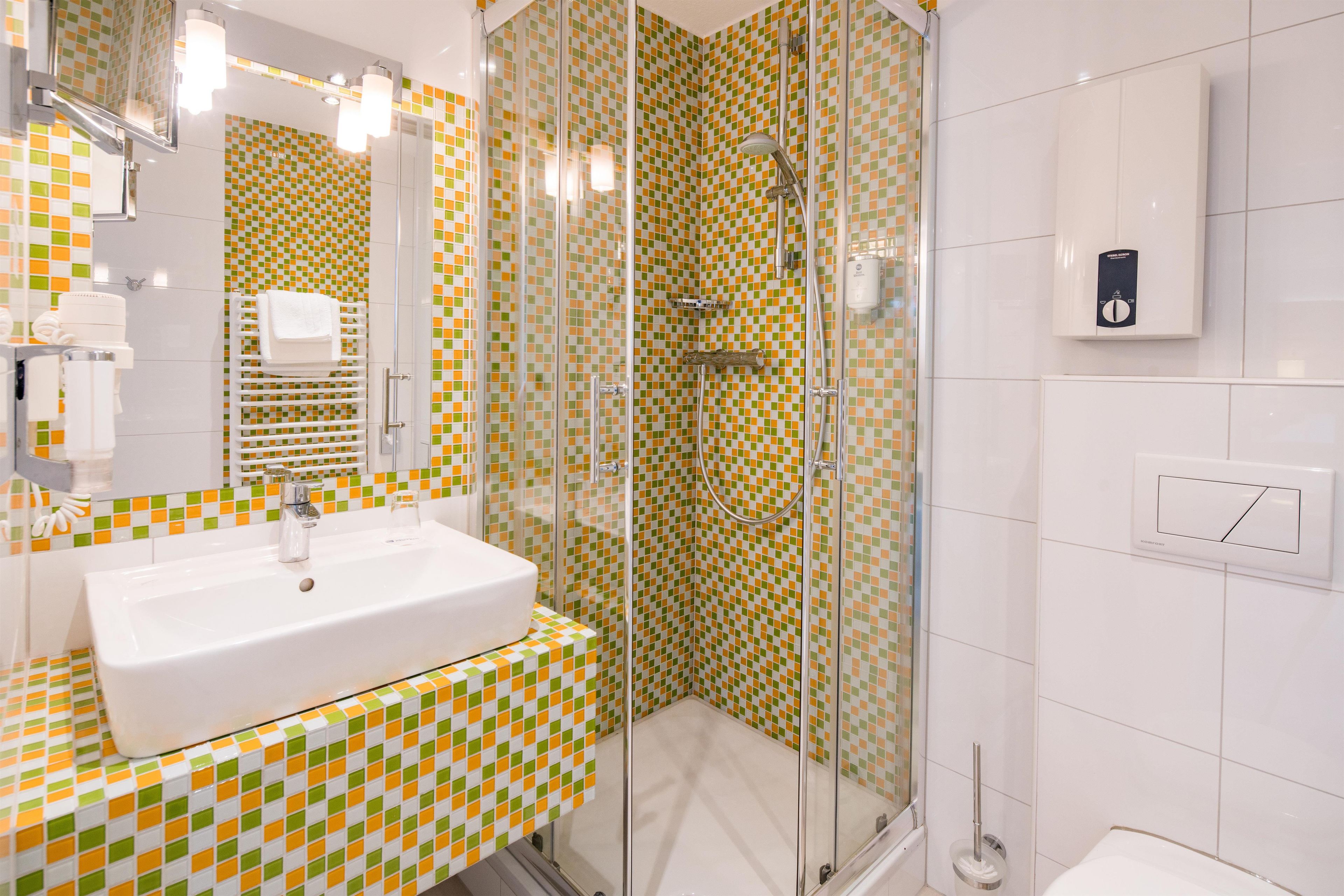 A bathroom with a checkered tile backsplash, a white sink, and a glass-enclosed shower area.