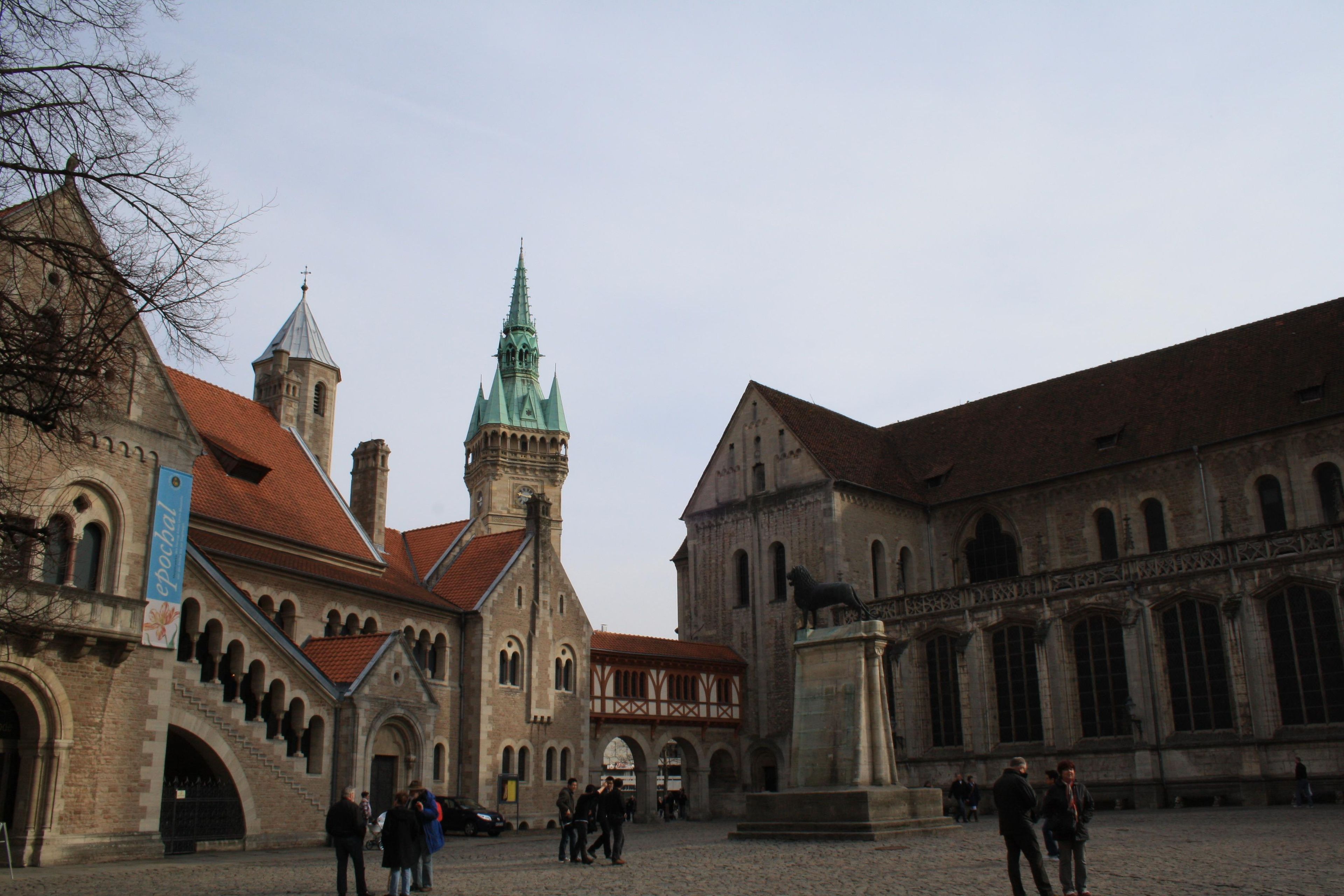A historic building with a prominent tower and a statue in front.