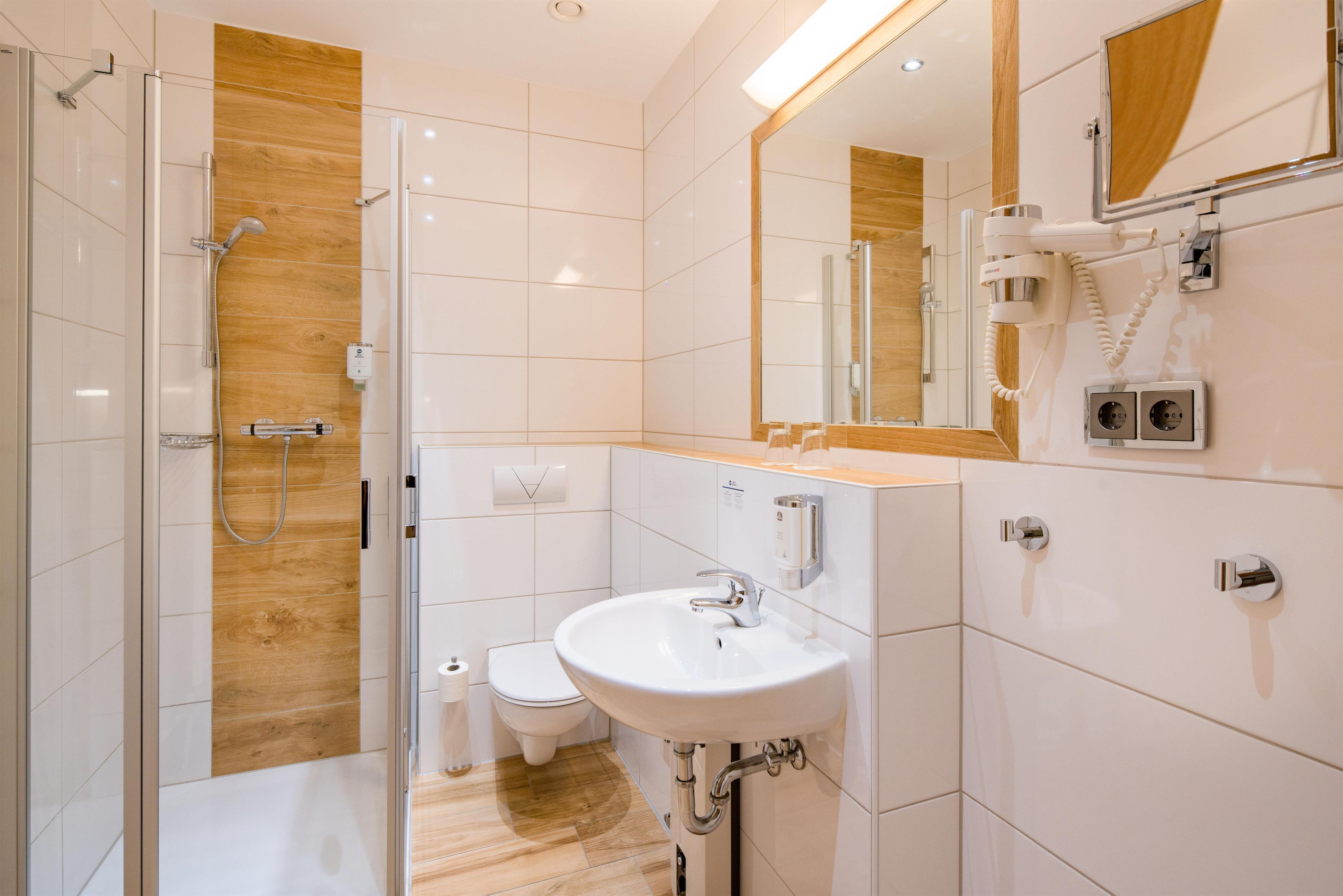 A modern bathroom with a glass shower enclosure, a white sink, and a toilet.