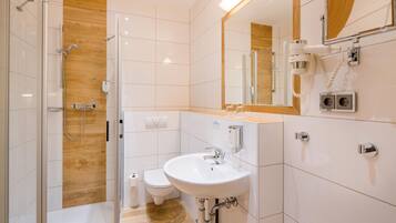 A modern bathroom with a glass shower enclosure, a white sink, and a toilet.