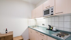 Una cocina moderna con microondas, pileta y una mesa de madera con una botella.