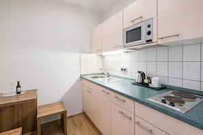 A modern kitchen with a microwave, sink, and a wooden table with a bottle. - Best Western City-Hotel Braunschweig (Braunschweig)