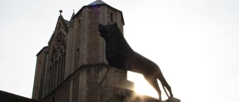 A statue of a dog on a building with a pointed roof and arched windows.
